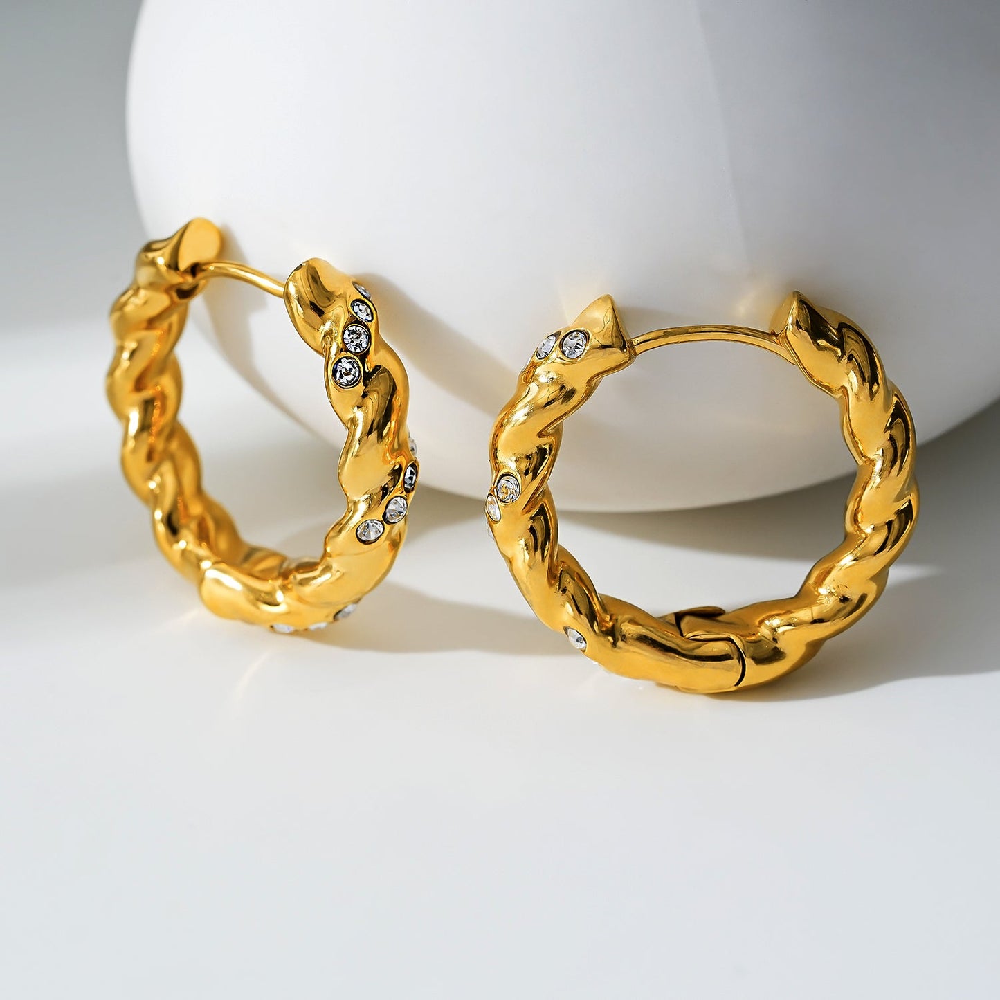 Style KAMENZ: Twisted Textured Hoop Earrings with Zirconia Embellishments.