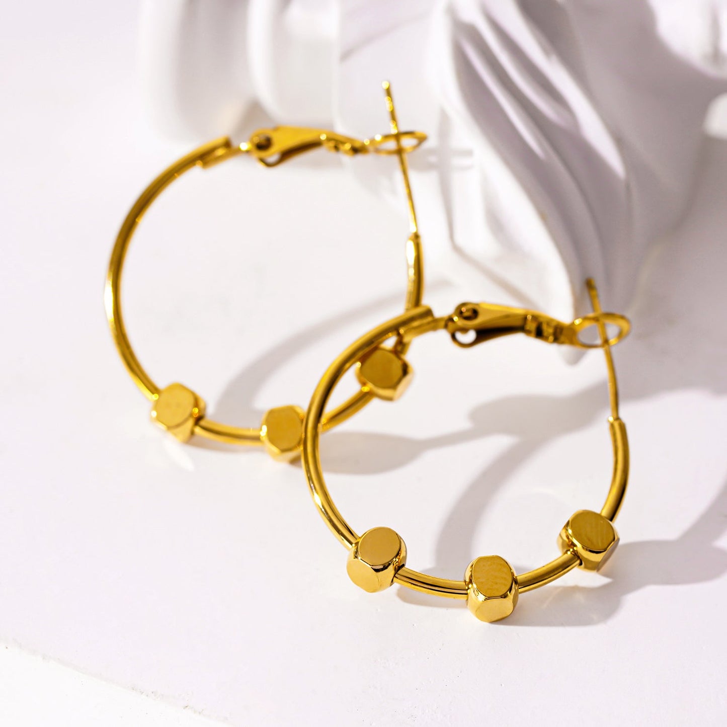 MASUYO: Avant-Garde Rounded Hoop Earrings Anchoring a Trio of Square Beads.