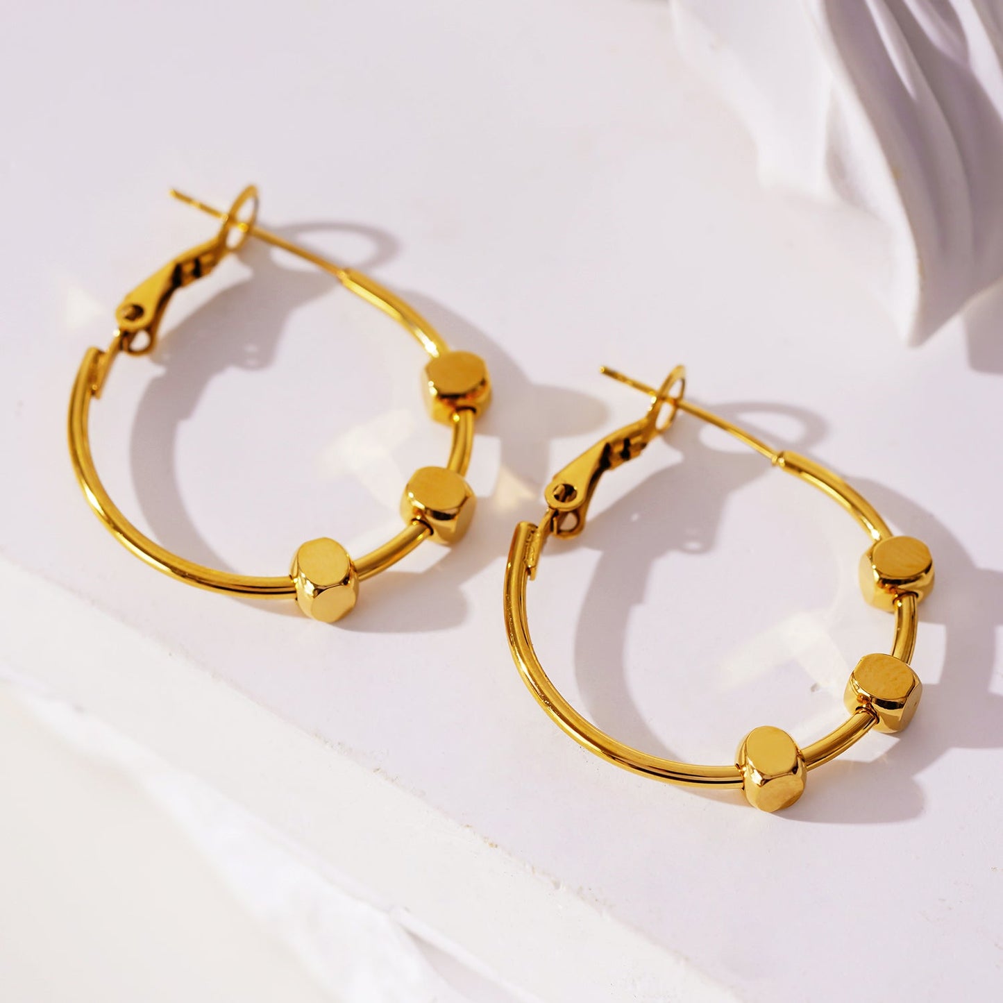 MASUYO: Avant-Garde Rounded Hoop Earrings Anchoring a Trio of Square Beads.