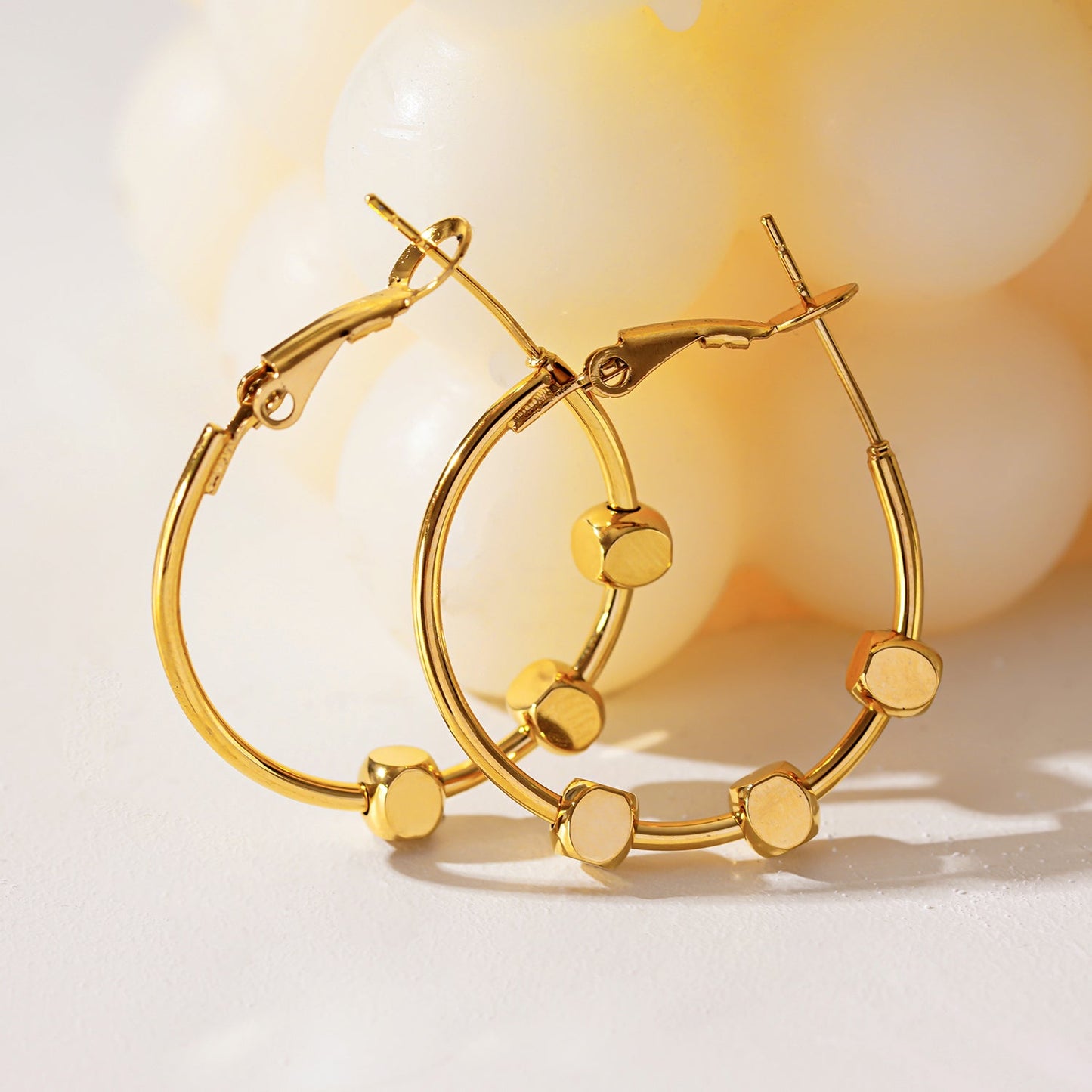 MASUYO: Avant-Garde Rounded Hoop Earrings Anchoring a Trio of Square Beads.